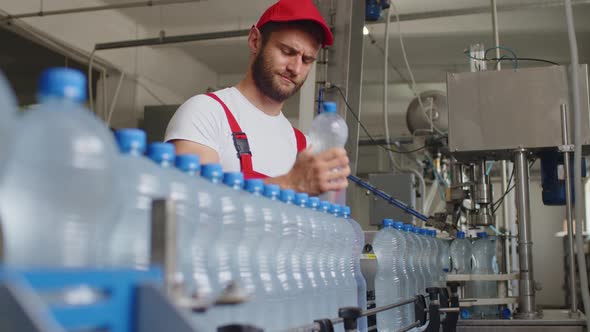 Young Man Worker of Water Factory Checking Quality and Making Inspection in Line Production