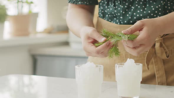 Anonymous person decorating sorbet with twigs alt