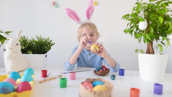 Cute boy coloring eggs for Easter holiday