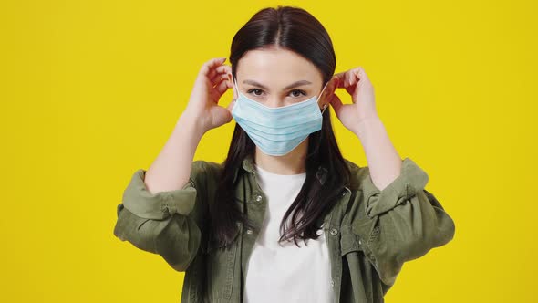 Beautiful Brunette Girl in a Green Shirt Standing on a Yellow Background Protecting Herself From alt