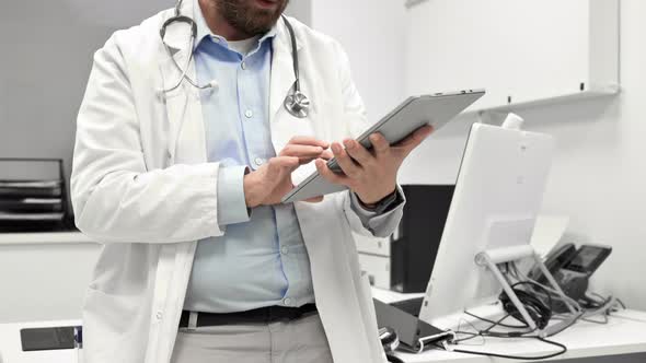 Male Doctor with White Coat and Stethoscope Using Tablet Network Connection in Hospital Room Medical alt