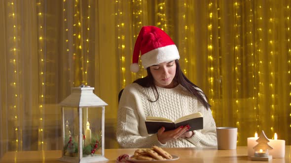 Relaxed Woman Santa Hat Reading Book Drinking Tea