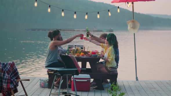 People Clinking Glasses at Outdoor Dinner Party on Lake Pier alt