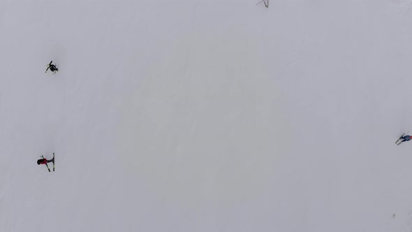 Aerial Top View of Skiers Go Down the Ski Slope on Ski Resort in Mountains alt