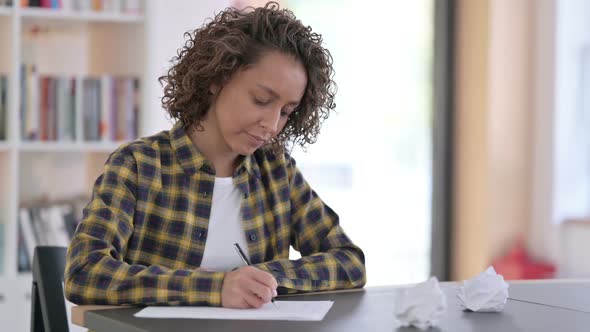 Disappointed Mixed Race Woman Trying to on Paper at Work alt