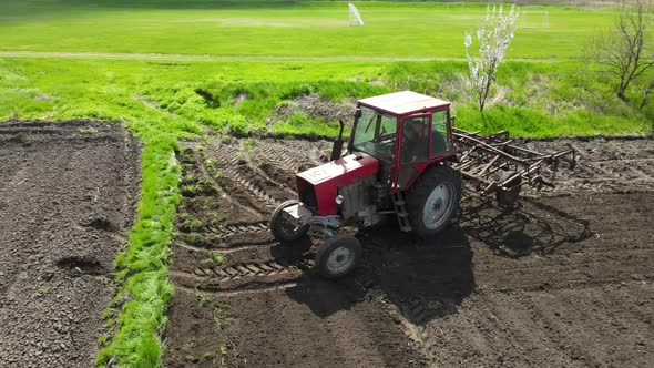Agricultural Red Small Tractor in the Field Plowing