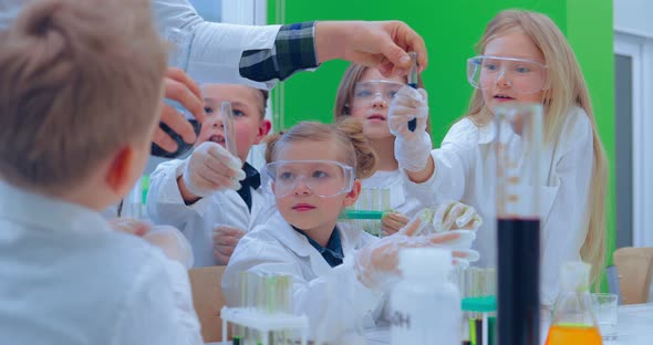 Teacher and Students Doing Science Experiment in School Classroom alt
