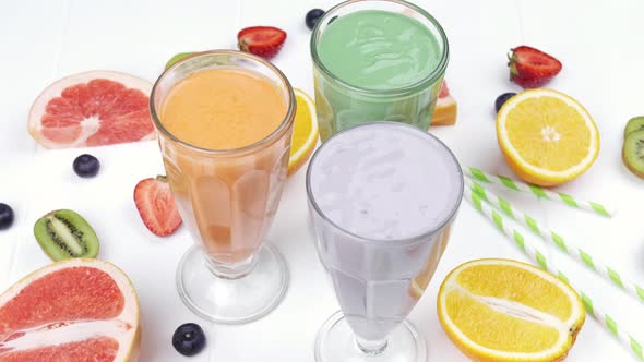 Three Different Milkshakes with Fruits on a Rustic White Wooden Background alt