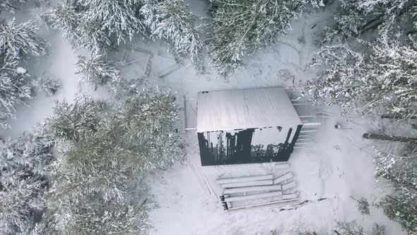 Aerial view of a small house with triangular roof near snow covered trees alt