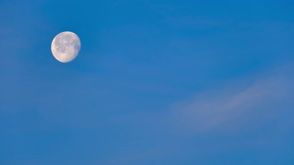 Big round moon in the blue daytime sky, time lapse