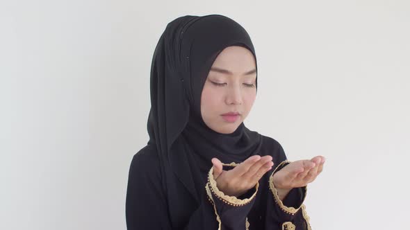 Happily young Muslim female praying with Islamic faith 