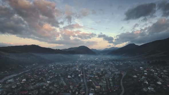 Biuldings in Transparent Mist Against Hills Silhouettes alt