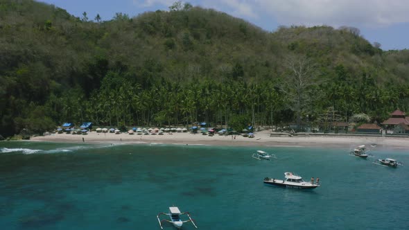 boats anchored in blue turquoise water of crystal bay nusa penida bali with tropical white sand beac alt