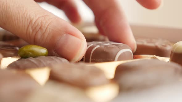 Female picking one chocolate from box of  many different 4K 2160p 30fps UltraHD footage - Woman chos alt