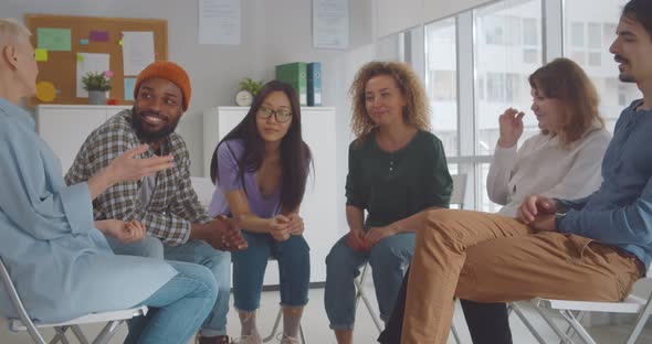 Group of Happy Multiracial People Joining Hands at Therapy Session alt