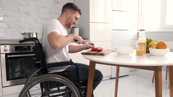 Disabled Young Man in Wheelchair Preparing Food In Kitchen alt