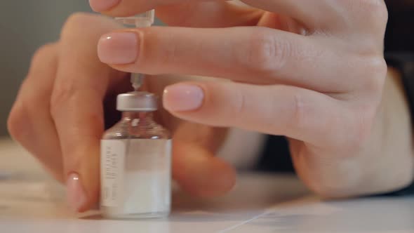 Closeup of Female Hands are Taking a Vaccine Into a Syringe with a Needle