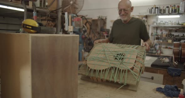 smiling Luthier lifts a glued guitar mold