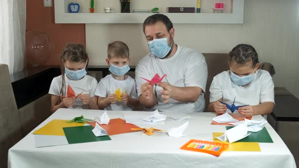 Dad with Children in Medical Masks Makes Paper Colored Origami Crane, Social Distancing and Self