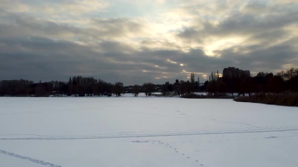 Aerial flying up on frozen wintery river in snow