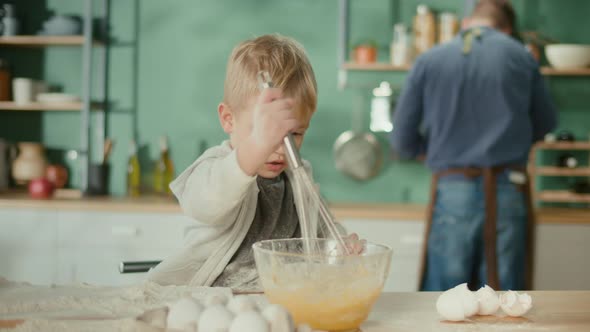 Boy Mixing Flour With Eggs and Other Ingredients Using a Hand Mixer alt