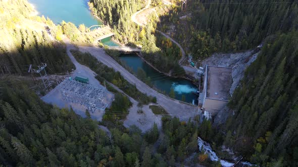 Descending aerial footage of water generating station in the Canadian Rocky Mountains with low sun. alt