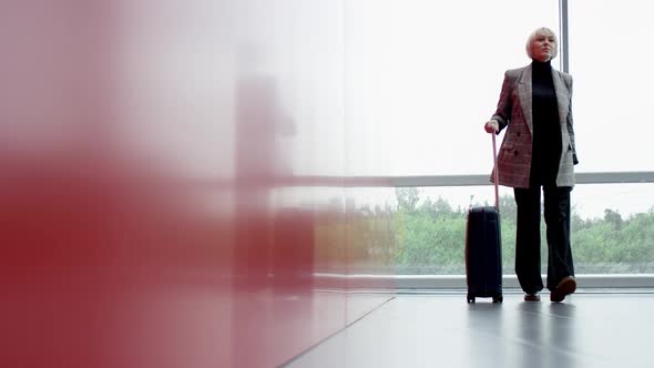 A Panoramic Shot of a Blonde Middle Aged Business Woman Gladly Proceeding with Her Hand Luggage To