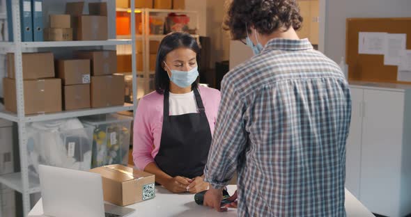 Back View of Male Client in Protective Mask Receive Order at Pickup Point and Pay with Credit Card alt