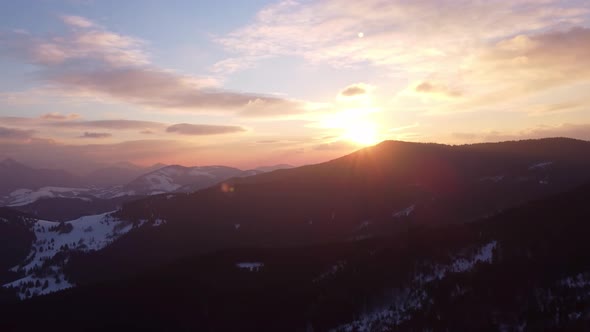 Aerial View of Winter Sunset Over Alpine Silhouette Mountains alt