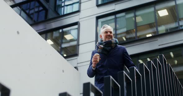 A Man with a Cup of Coffee Descends the Stairs Near the Modern Office Center alt