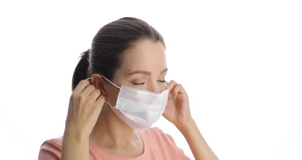 Young Beautiful Caucasian Woman is in a Medical Mask on the White Background