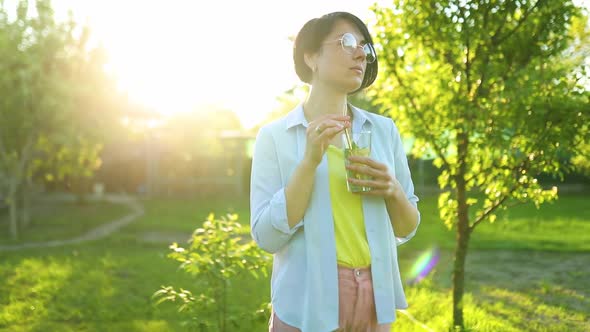 Woman drinking summer citrus lemonade with reusable metal straws party