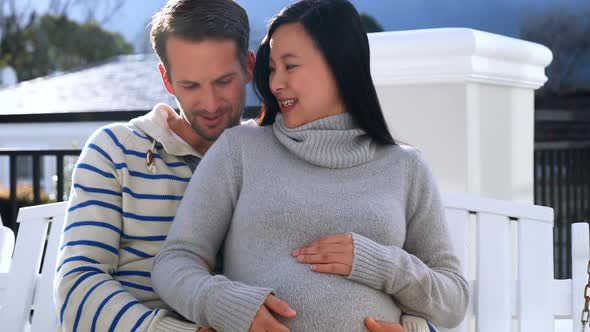 Pregnant couple sitting in swing  alt