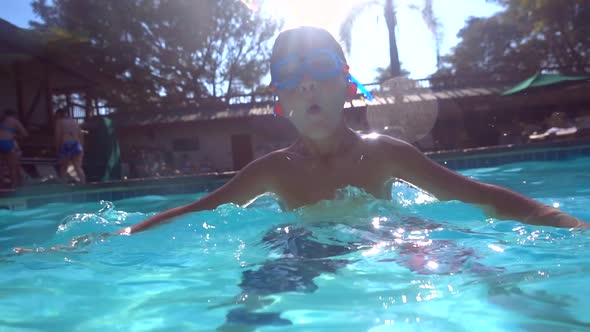 Underwater shot of a boy playing in a pool at a hotel resort. alt