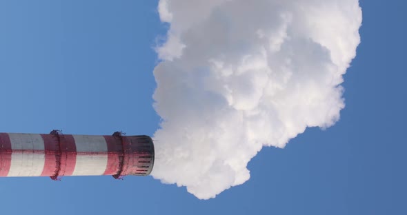 Thick White Smoke Escapes From the Chimney of the Thermal Power Plant and Dissipates Into the Blue