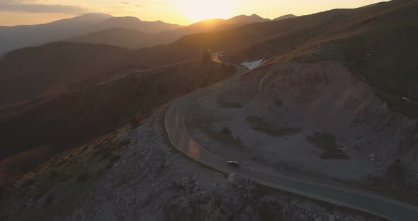 Black Car Driving on Lonely Mountain Road at Dayend. Traveling Journey in the Spring alt