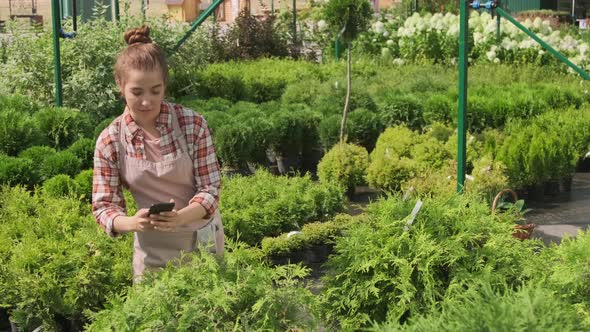 Female Gardener Using Smartphone In Yard alt