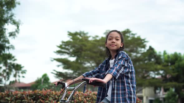 Little girl sitting on a bicycle and looking at the camera, Smiling kid on a bicycle