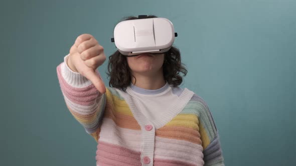 Woman showing thumb down while using VR virtual reality headset over an blue background alt