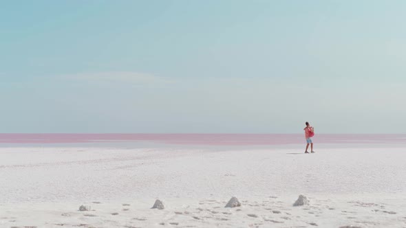 Wide Landscape Shot with Beautiful Couple in Pink Wear on White Salty Coast Looks Like Desert Man alt
