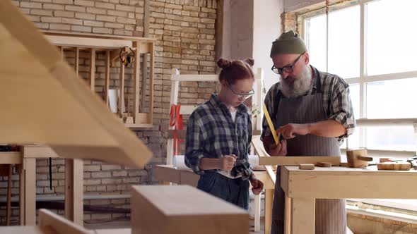 Aged Craftsman with Teenage Girl in Workshop alt
