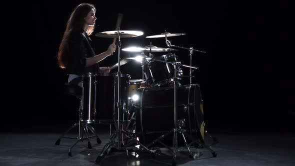 Drummer Girl Starts Playing Energetic Music, She Smiles. Black Background. Slow Motion alt