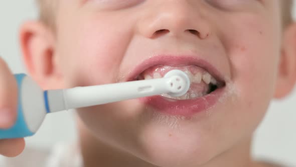 Portrait Happy Smiling Child Kid Boy Brushing Teeth with Electric Toothbrush on White Brick alt