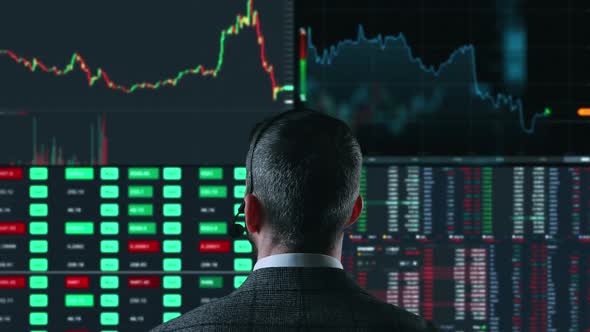 Trader is Working with Multiple Computer Screens Full of Charts and Data Analysis and Stock Broker alt