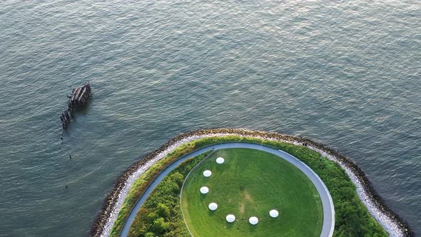 aerial top down shot, then tilt up from round green park area to reveal golden hour sunset & the New alt