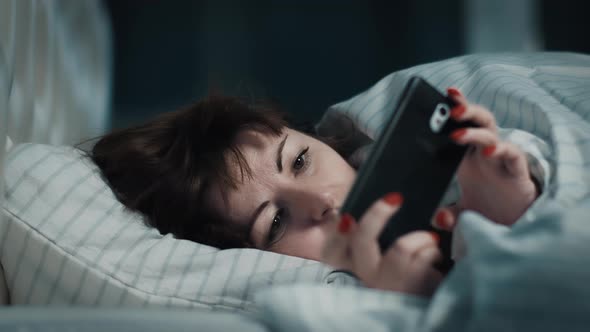 Cinematic Sleepy Pretty Woman Lies on the Bed and Uses the Phone an Evening Alone Cinematic