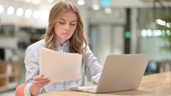 Serious Businesswoman with Laptop Reading Documents in Office alt