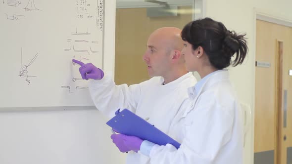 Scientist analyze and discuss research data on white board in science laboratory alt