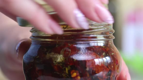 A Woman Closes A Lid On A Jar Of Sun Dried Tomatoes Drenched In Olive Oil. Cooking At Home. alt