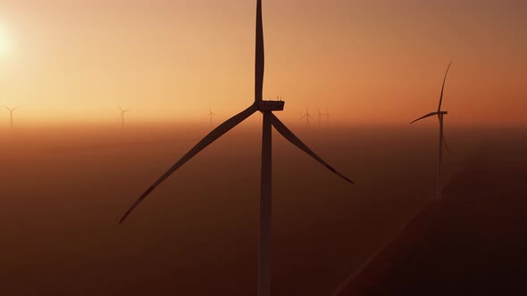 Windmills Rotate at Sunset in Fog on Offshore Station